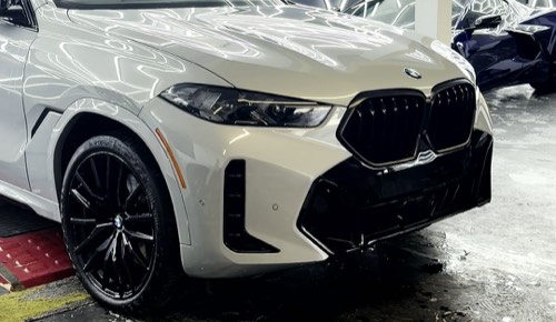 BMW X6 M in satin sand under the hex lighting of the Obsidian Wrapz bay