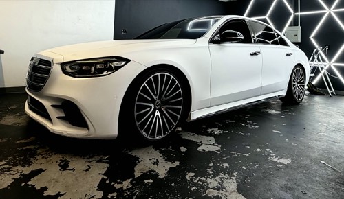 Satin white Mercedes S-Class, front three-quarter under the hex lighting of the Obsidian Wrapz bay